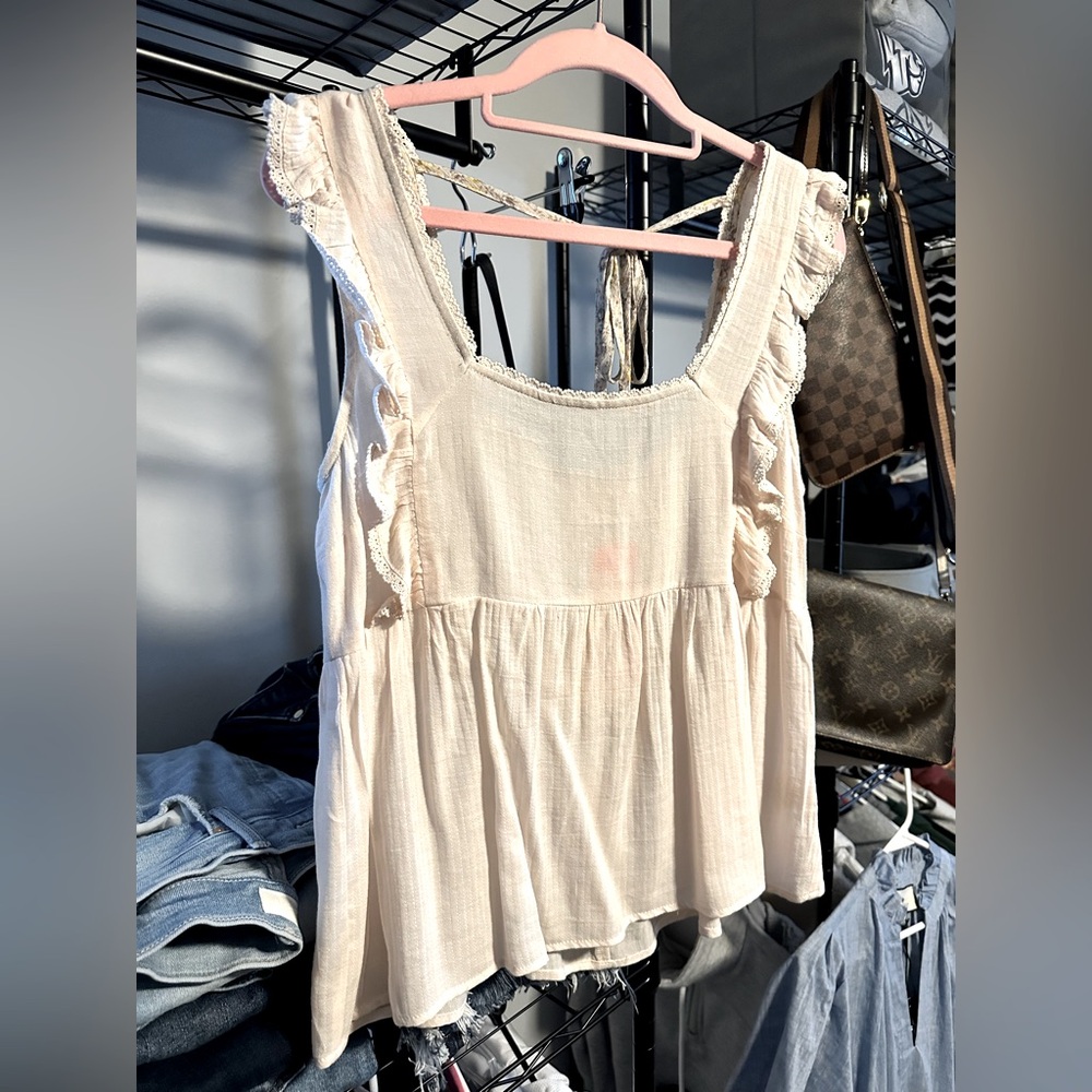 NWT Women’s cream tank top. Ruffled edge, tie back detail.